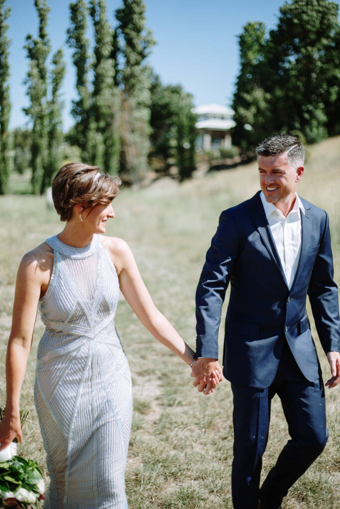 Camilla and Jason smile at each other on a grassy path at Flowerdale.