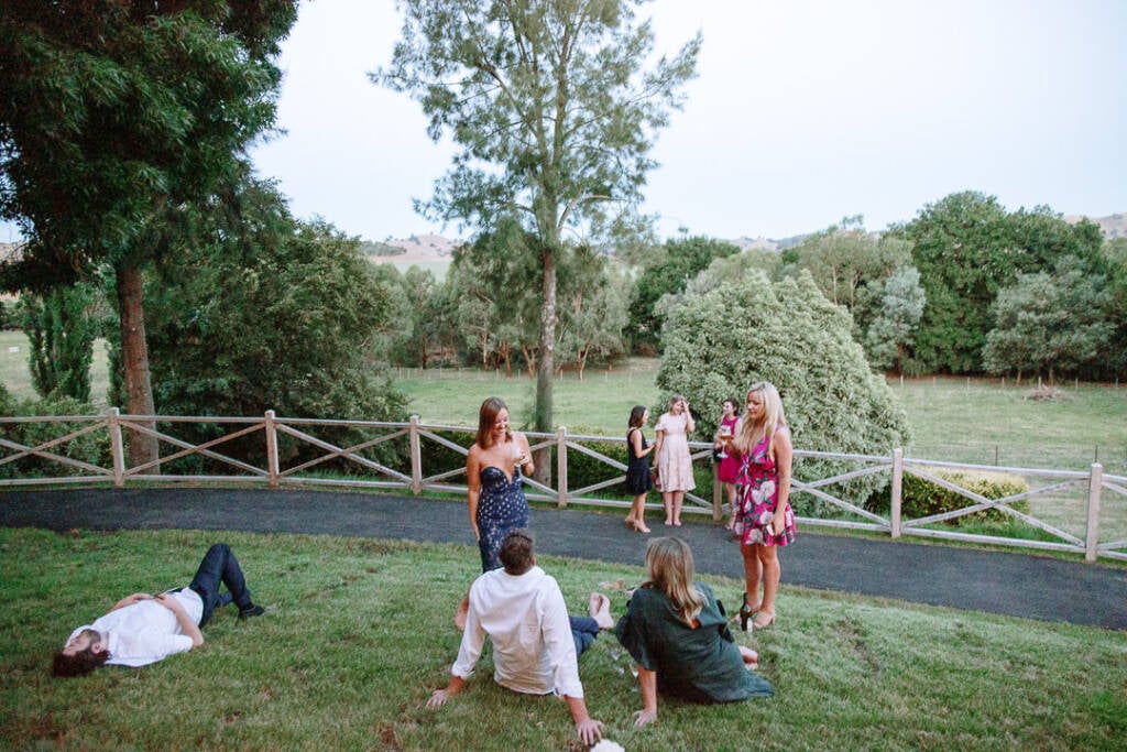 Guests sit and chat on the lawn beside a timber fence at Flowerdale Estate.