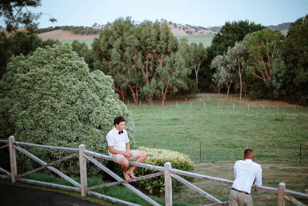 Two wedding guests rest beside a fence overlooking the paddocks at Flowerdale Estate.