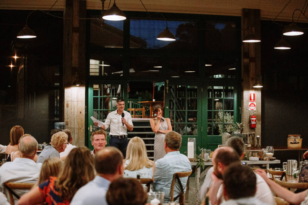 Wide view of Camilla and Jason speaking to seated guests at Flowerdale Estate.