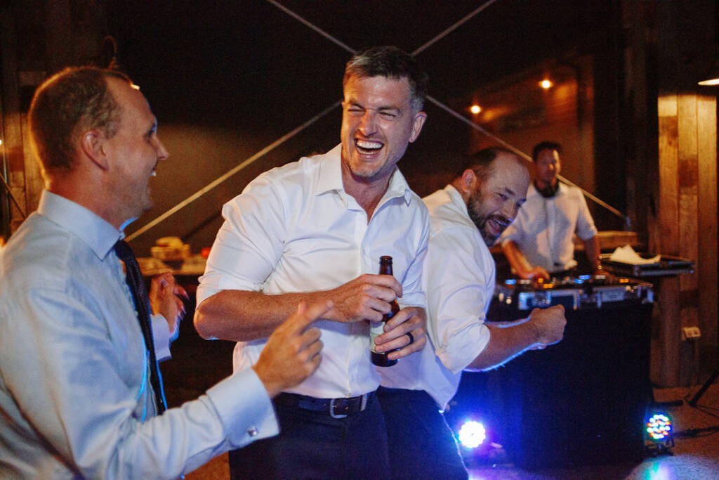 Jason laughs with guests beside DJ equipment during the Flowerdale reception party.