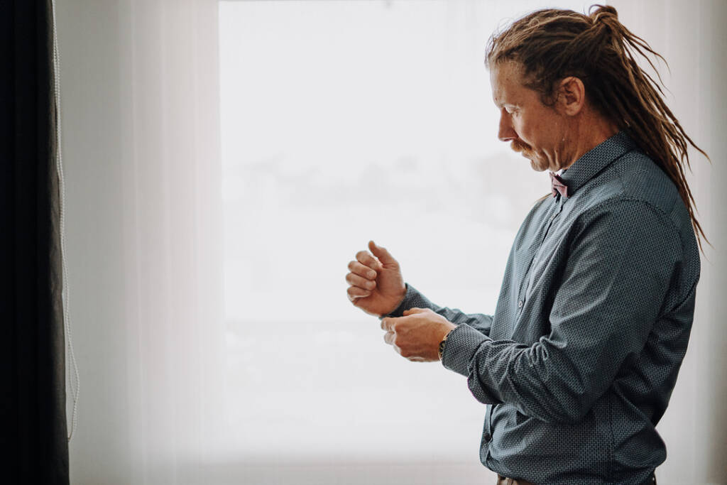 Dale adjusts his shirt cuff beside a bright window at Royal Hotel Sea Lake.