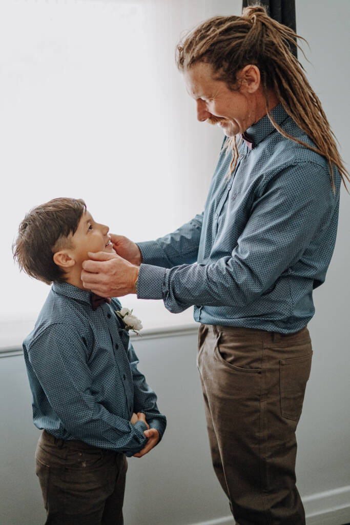 Dale holds a child’s cheeks as they smile at each other before the ceremony.