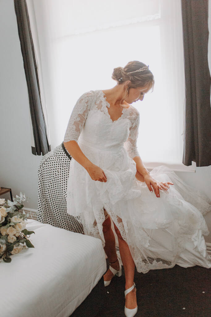 Bethany lifts her lace skirt to reveal white slingback wedding shoes.