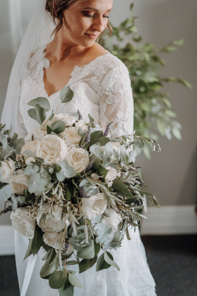 Close-up of Bethany’s lace bodice and white-flower bouquet as she looks down.
