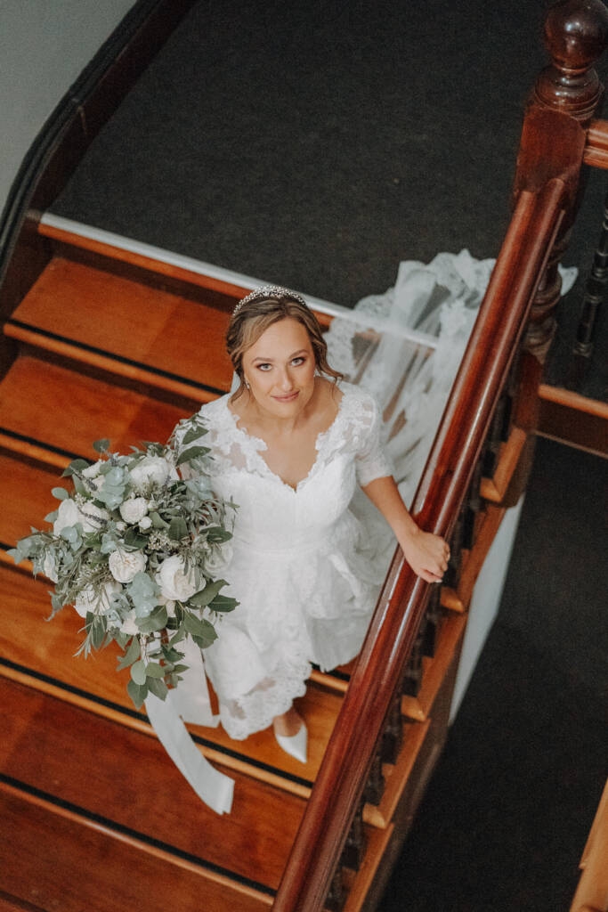 Bethany looks up towards the camera on the Royal Hotel’s timber staircase.