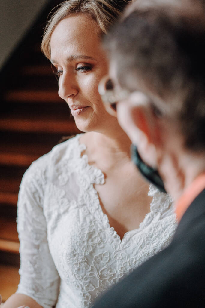 Bethany looks aside beside a suited guest during a close-up bridal portrait.