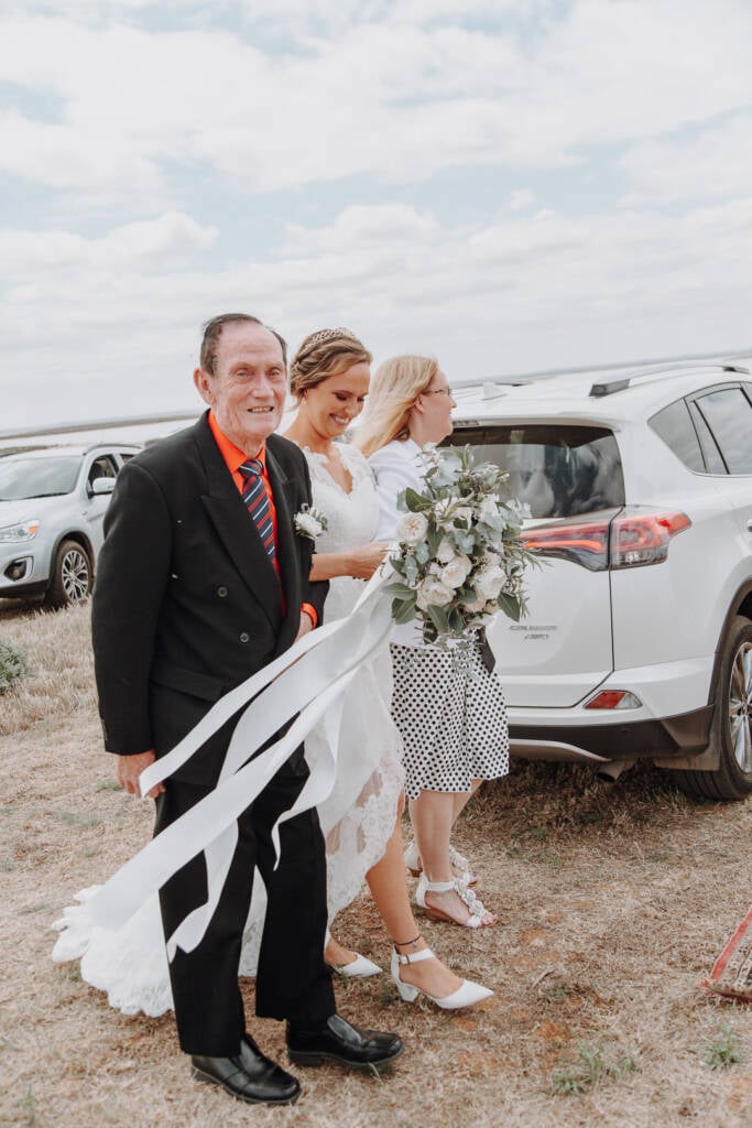 Bethany walks with two guests past parked cars towards the Lake Tyrrell ceremony.