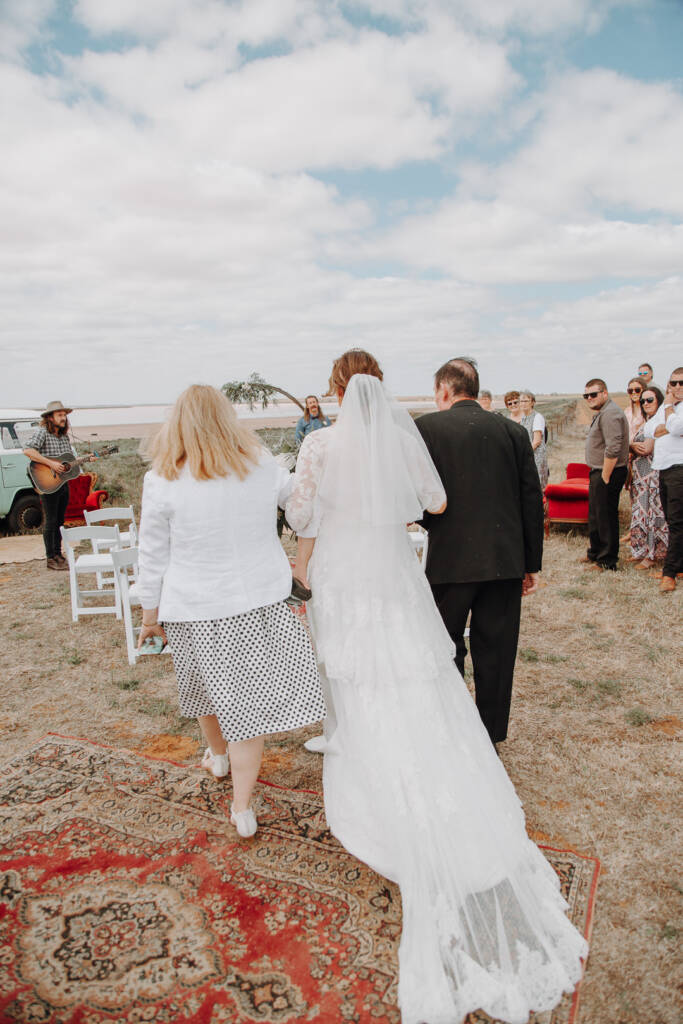 Bethany walks down the rug aisle beside a guitarist at Pink Lake Reserve, Lake Tyrrell.