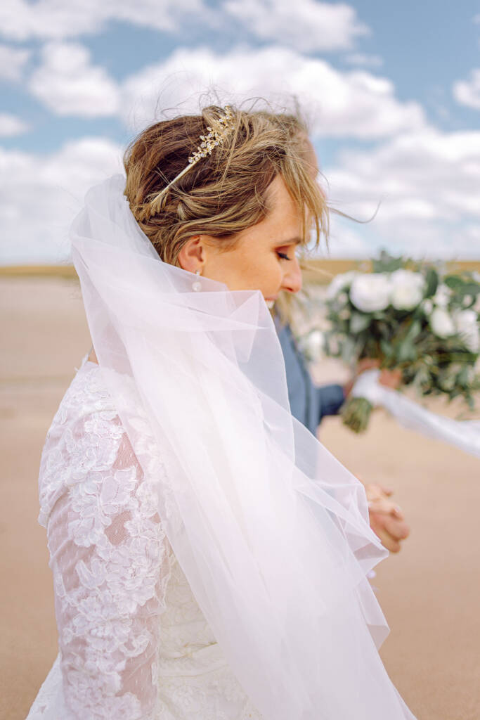 Close-up of Bethany’s braided updo, jewelled hairpiece and windblown veil.
