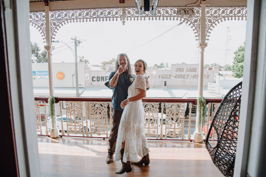 Dale points towards the camera beside Bethany in her shorter reception dress at Royal Hotel Sea Lake.
