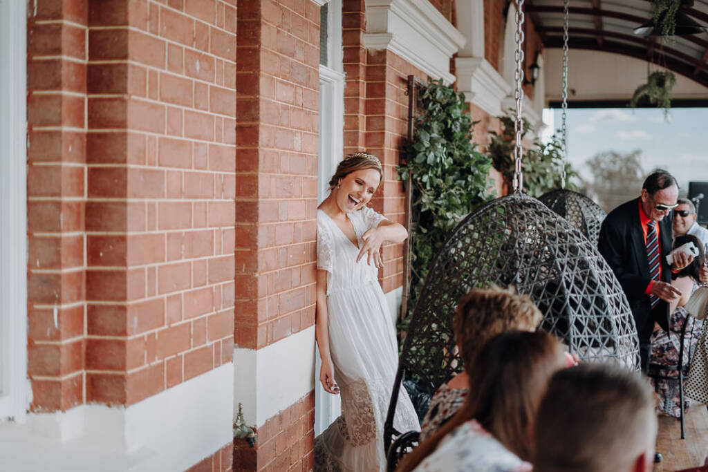 Bethany laughs beside the Royal Hotel’s brick doorway and hanging egg chairs.