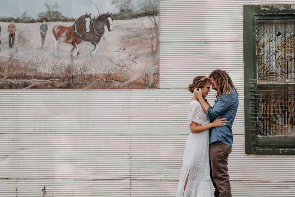 Bethany and Dale touch foreheads beside a horse mural on a street near Royal Hotel Sea Lake.