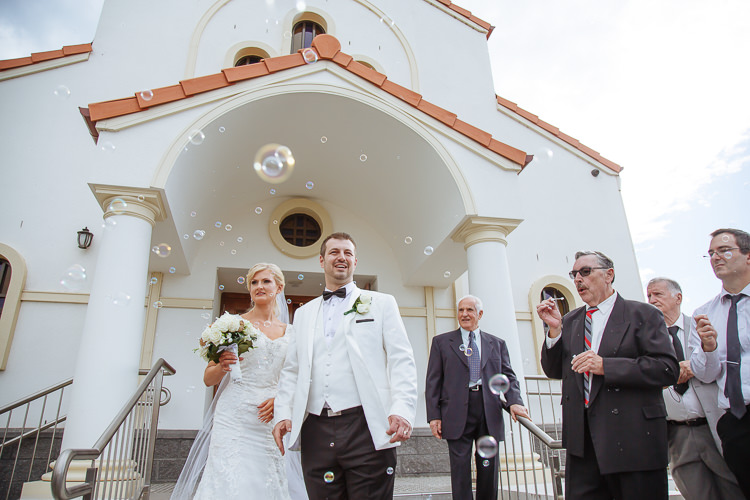 Aggie and Alex leave Holy Epiphany church in Frankston through floating bubbles on the steps.