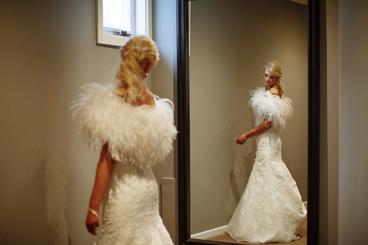 Aggie wears a feather wrap beside a tall mirror at Lindenderry.