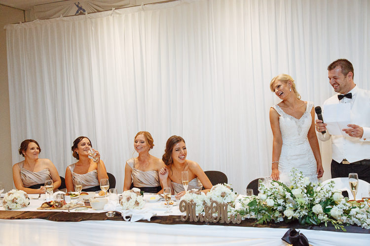 Alex holds speech notes beside Aggie as bridesmaids laugh at the bridal table at Lindenderry Red Hill.