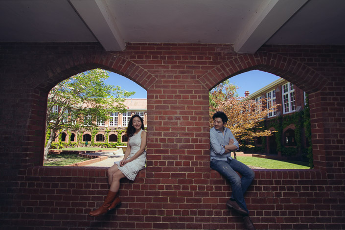 The couple sit in separate brick arches at Geelong Grammar School's Corio campus, smiling towards each other.