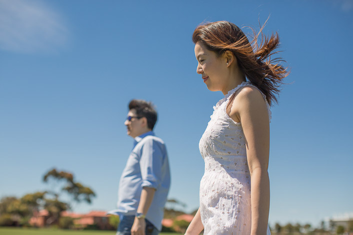The woman's profile against a deep blue sky, white broderie dress bright in the sun.