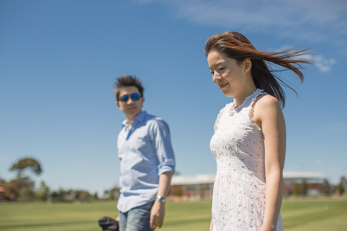 Eyes closed to the breeze, the woman smiles while the man looks on in sunglasses.