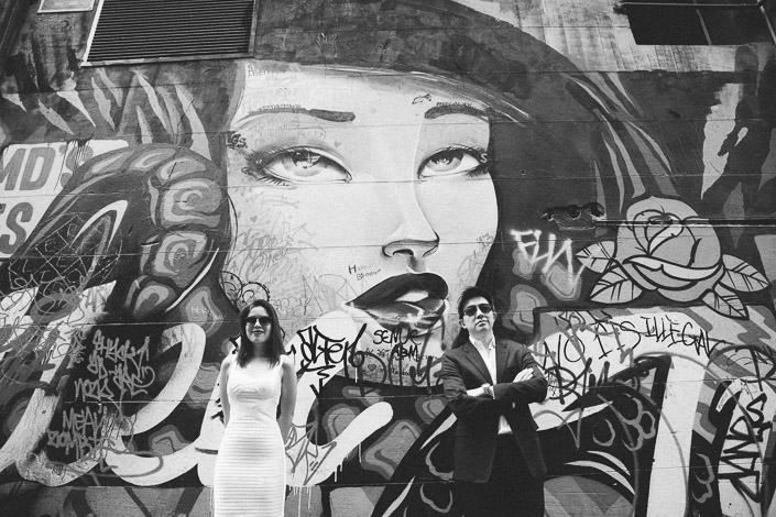 The couple pose in sunglasses before a large mural in Hosier Lane, Melbourne CBD.