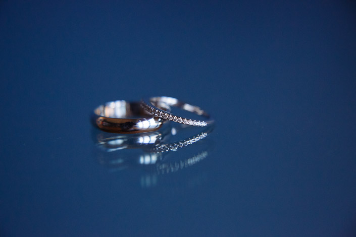 Two bands rest on blue glass, the pave ring balanced against gold