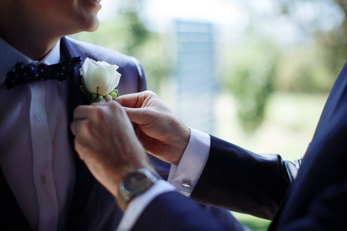 A white rose boutonniere pinned to the navy lapel