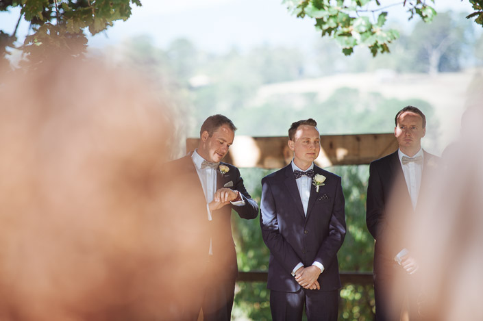The groom waits at the Paynes Rise Wines arbour as a groomsman checks his watch.