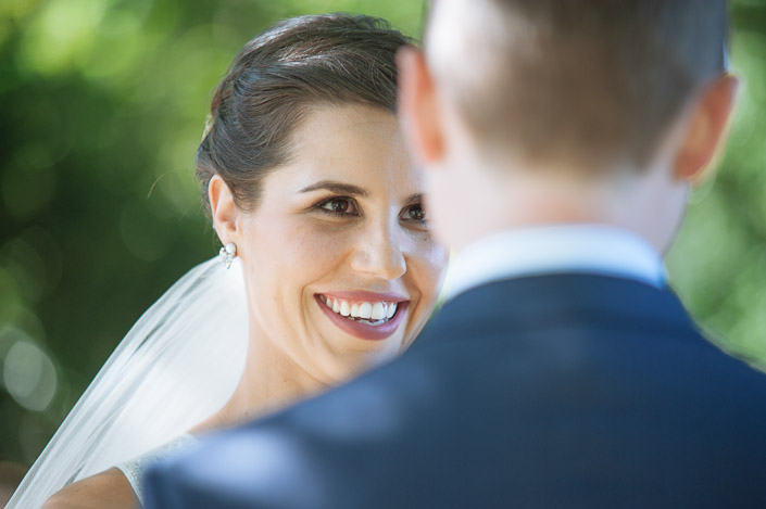 Every part of the bride's face is in on this smile, the groom's head blurred in front.
