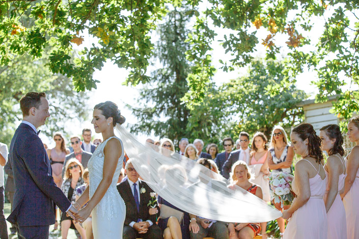 The bride’s veil lifts between the couple during the outdoor ceremony at Payne’s Rise Vineyard.