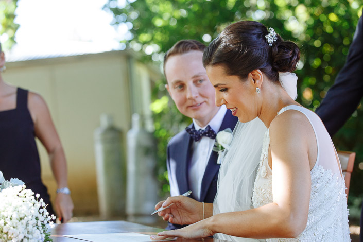 Pen poised over the register, the jewelled comb bright in the bride's bun, the groom beside her.
