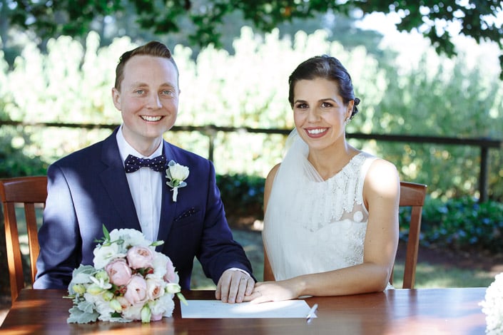 The bride and groom smile at the signing table at Payne’s Rise Vineyard.