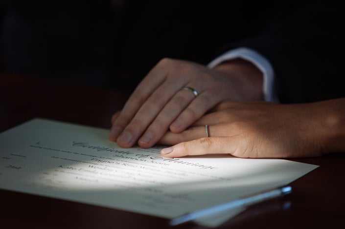 New rings layered over the Certificate of Marriage, a pen beside the page.