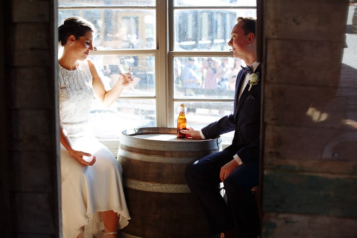 The newlyweds toast across a wine barrel inside the timber room at Paynes Rise Wines.