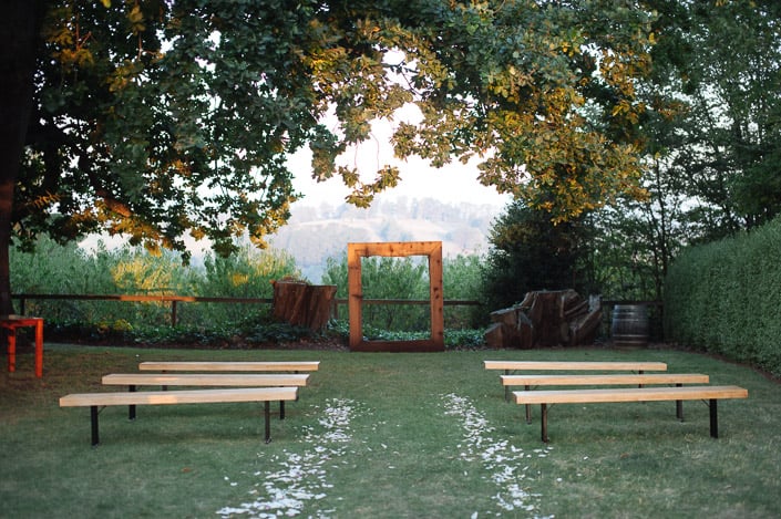 Petals line the empty tree-shaded ceremony aisle at Paynes Rise Wines at dusk.