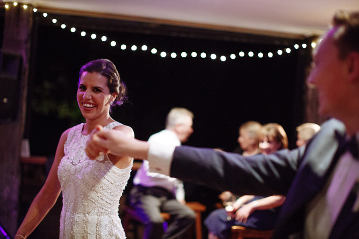 The bride dances beneath fairy lights at the Paynes Rise reception as the groom holds her hand.