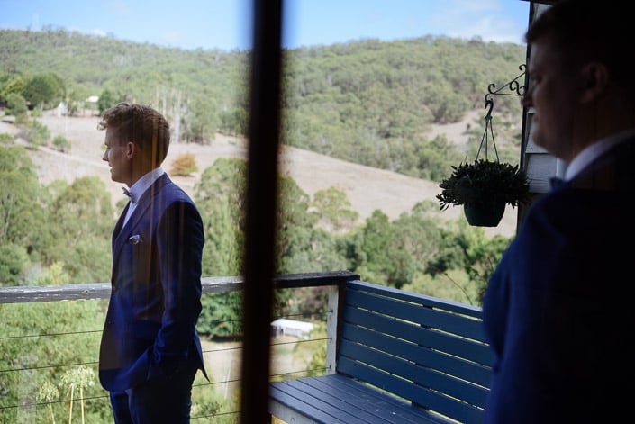 The groom looks over the bushland from a Pennyroyal Retreat cottage in his blue suit