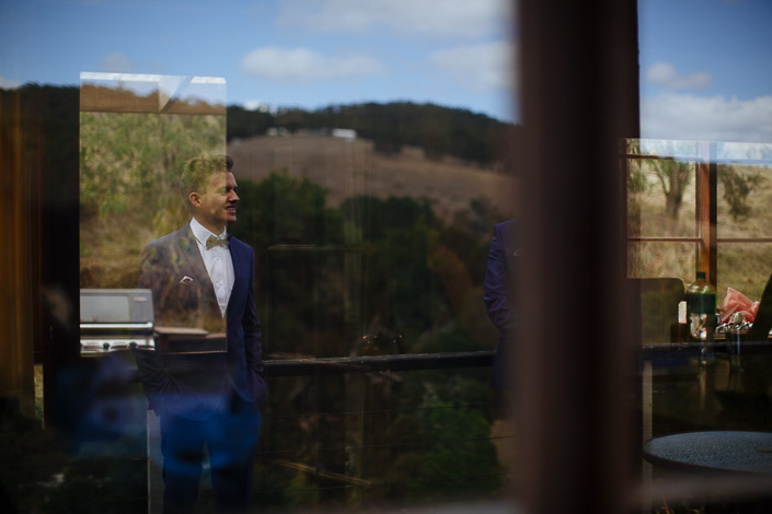 The groom is reflected in a Pennyroyal Retreat cottage window with the hills beyond