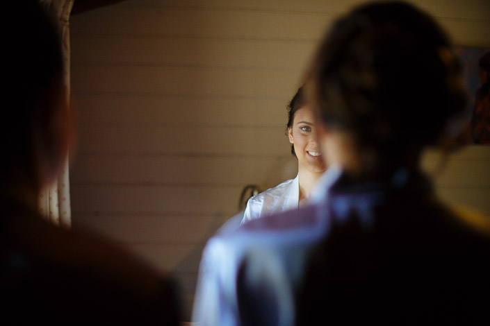 The bride smiles between two attendants during her wedding preparation
