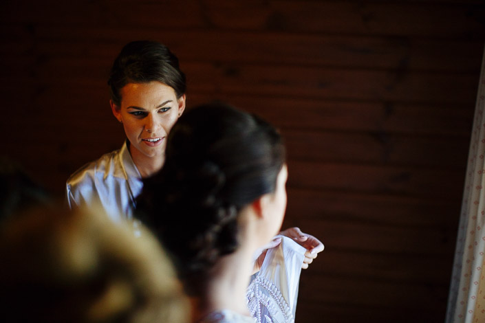 A bridesmaid steadies the sleeve as the gown settles