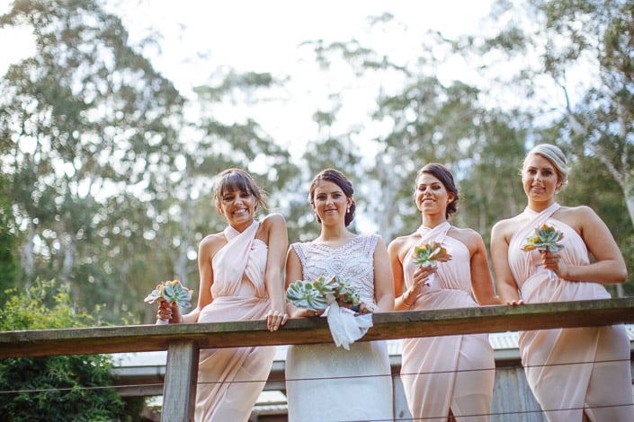 The bride and three bridesmaids pose together with succulent posies