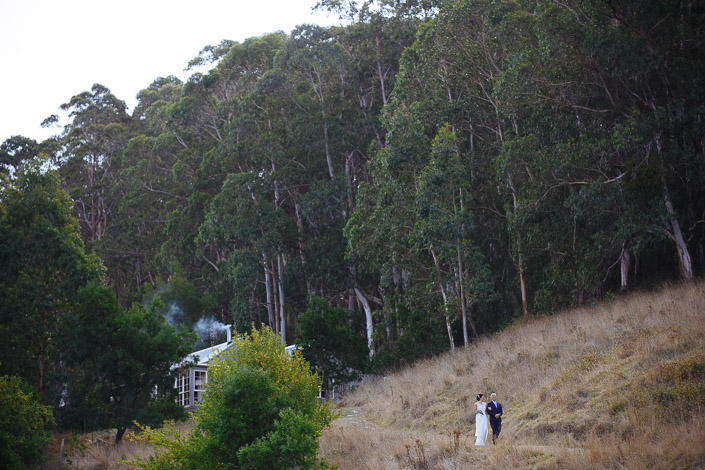 The bride and a silver-haired man descend past a cottage beneath the gums at Pennyroyal Retreat