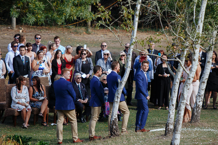 The groomsmen turn as the guests raise their phones