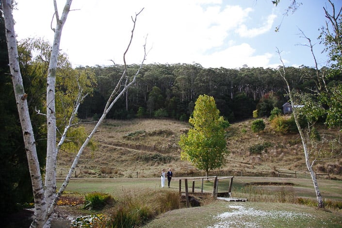 The bride and a silver-haired man approach the little footbridge at Pennyroyal Retreat