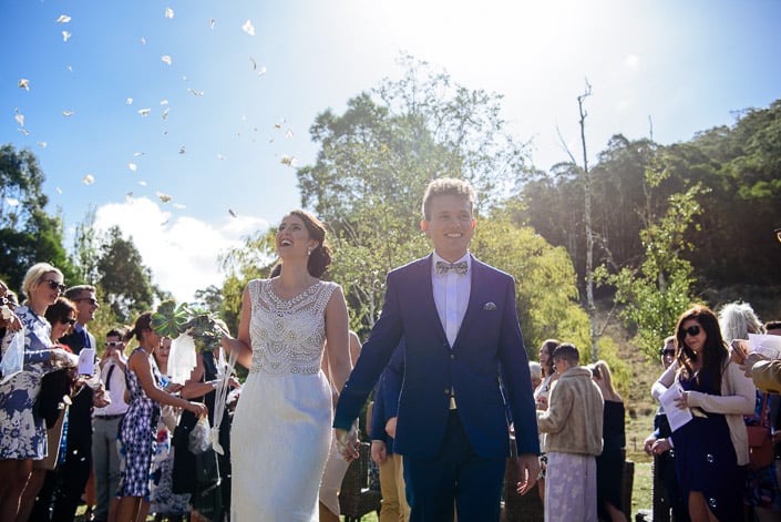 Guests throw petal confetti as the newlyweds walk back down the aisle