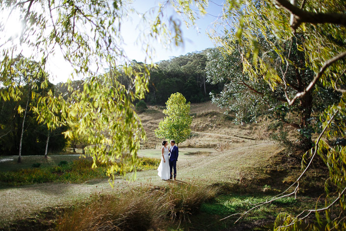The couple stand near the lake beneath willow branches at Pennyroyal Retreat