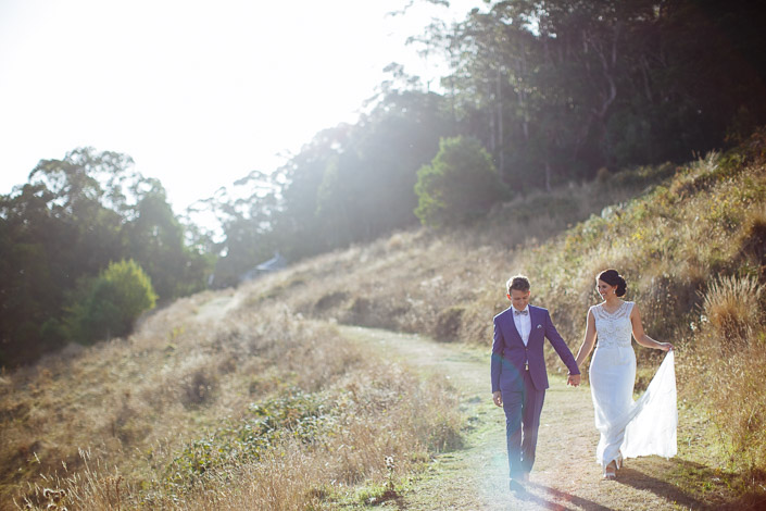 The groom leads the bride down a Pennyroyal Otways Retreat farm track in warm late light