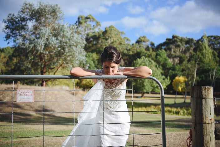 The bride rests on a Pennyroyal Otways Retreat farm gate beside a Please Shut Gate sign