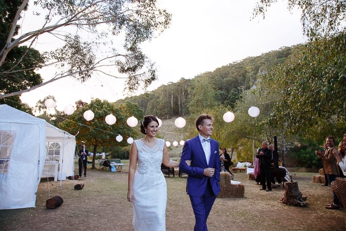 The couple arrive at the lantern-strung reception clearing at Pennyroyal Retreat