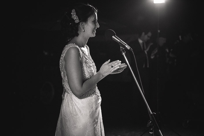 A monochrome bride speaks her thanks into the standing mic