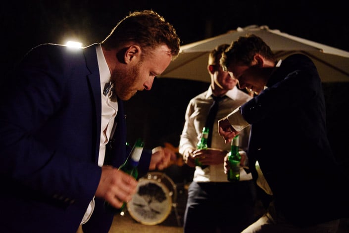 Heads down, the groomsmen compare moves under the umbrella